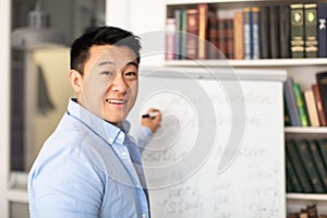 Korean Tutor Man Writing On Whiteboard Teaching English In Classroom