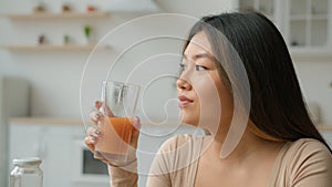 Korean woman drinking fresh smoothie orange juice. Asian vegetarian girl tasting glass of vitamin fruity cocktail peach