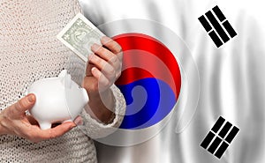 Korean woman with money bank on the background of Korea flag. Dotations, pension fund, poverty, wealth, retirement concept