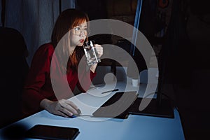 Korean woman working late time with laptop computer drinking water home office