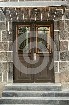 Black double leaf iron door covered with wrought iron decorative grating on the facade of a stone building