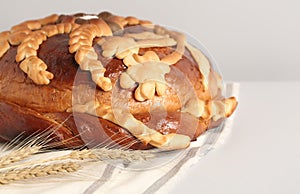 Korovai with wheat spikes on white table, closeup. Ukrainian bread and salt welcoming tradition