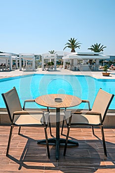 Cafe table and chairs near swimming pool in Greek resort hotel