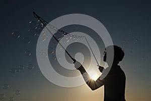 Silhouette boy playing with a bubble wand on the beach