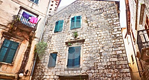 Kotor narrow small streets of historical old town. House drying linen bright sun blind old stone. Authentic structures. No body