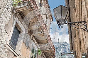 Kotor Old Town`s ancient tall stone houses and dramatic mountains seen between them in the distance