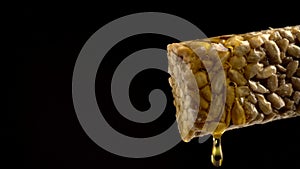 Kozinak dessert of sunflower seeds pour honey on a black background close-up copy space