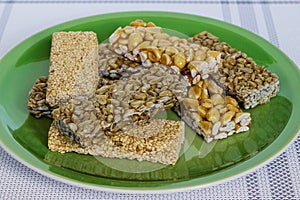 Kozinaki with seeds, nuts, sesame seeds and honey in a green plate. Useful snacks. Fitness diet food, nutritious snack, sesame