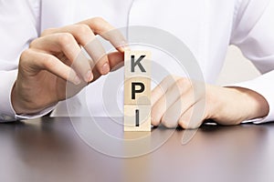 KPI, Key Performance Indicator text on cube blocks in businessman hands, man in white shirt