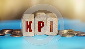KPI Word Written In Wooden Blocks with coins around. ,Key Performance Indicator business concept