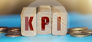 KPI Word Written In Wooden Blocks with coins around. ,Key Performance Indicator business concept