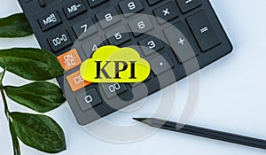 KPI - word on a yellow note sheet on a white background with a calculator, pencil and green sheet