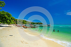 KRABI, THAILAND- MARCH 2018: Pretty women girls in bikini wimming in azure sea and long tail boats on a white sandy beach on Ko