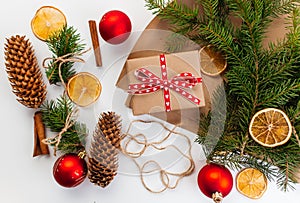 Kraft cardboard gift box tied with rough jute rope on gray wooden background with branches of Christmas tree and