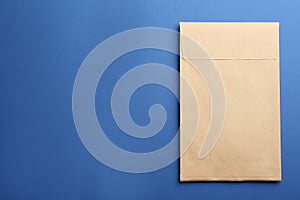 Kraft paper envelope on blue background, top view. Space for text