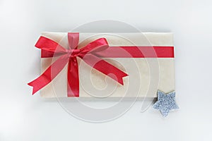 A kraft paper envelope tied with a red festive ribbon is meant to be a gift for