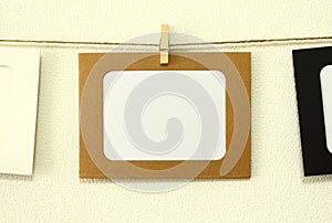 Kraft paper frame hanging on lacing on white wall background with space. There is empty space in the frame for text.