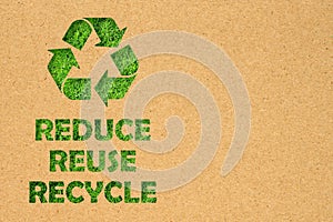 Kraft paper hole of Reuse, Reduce, Recycle symbol and text on green grass background. Environmental conservation concept