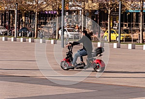 Krasnodar, Russia - December 10 2020: Alternative commute, man hiring and riding on a e-bike in a city park