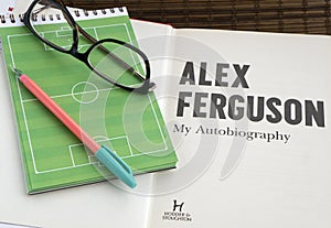 Reading autobiography book by Alex Ferguson, a football coach. Glasses photo