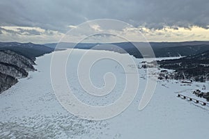 Krasnoyarsk dam and power plant on Enisey river from aerial view. Krasnoyarsk reservoir. Mountains landscape winter panoram snow