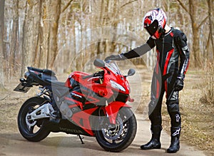 KRASNOYARSK, RUSSIA - April 21, 2018: Beautiful motorcyclist in full gear and helmet on a red and black Honda 2005 CBR 600 RR