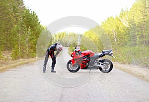 KRASNOYARSK, RUSSIA - April 27, 2018: Beautiful motorcyclist in full gear and helmet on a red and black Honda 2005 CBR 600 RR