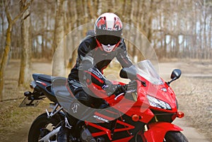 KRASNOYARSK, RUSSIA - April 21, 2018: Beautiful motorcyclist in full gear and helmet on a red and black Honda 2005 CBR 600 RR PC3