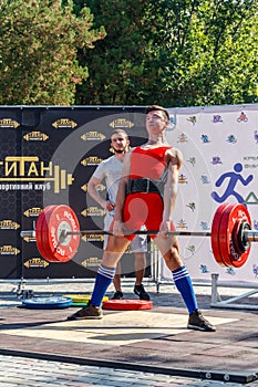 Young boy does an exercise with a barbell