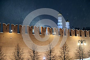 The Kremlin Wall and cathedrals after it in Moscow Russia with holiday lighting during cold Russian winter blizzard in night