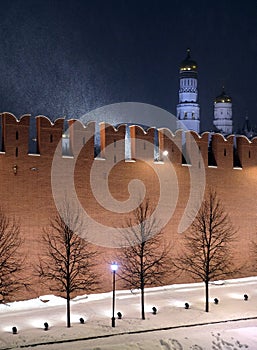 The Kremlin Wall and cathedrals after it in Moscow Russia with holiday lighting during cold Russian winter blizzard on night
