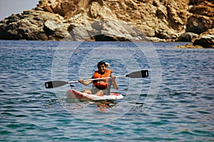 Kreta or Crete  Greece - A man in life jacket floating on a kayak in a sea against blurred rocky mountain in the background. Water