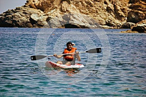 Kreta or Crete  Greece - A man in life jacket floating on a kayak in a sea against blurred rocky mountain in the background. Water photo