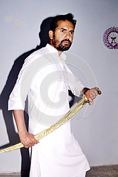 Kshatriya youth, wearing white kurta while shooting photo with sword. Indian hindu traditional costumes