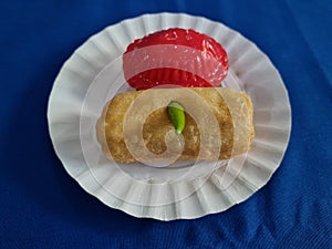 Ku cake and rissoles in a white container on a blue cloth background