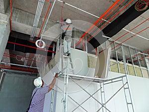 Drywall installation work in progress by construction workers at the construction site.