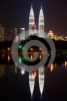 Skyline of Kuala Lumpur city at night with Petronas twin towers reflecting in the pond in Kuala Lumpur, Malaysia.