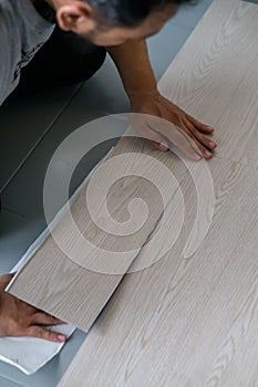 Kuala Lumpur, Malaysia - MA man installing new vinyl tile floor, a DIY home project