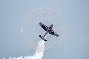 Silhouette of an airplane with trail of smoke behind against background of blue sky.