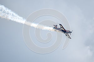 Silhouette of an airplane with trail of smoke behind against background of blue sky