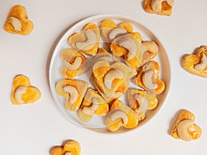 kue kering kacang mede or cashew cookies. made from butter, flour, egg and topped with cashew nut. served on white plate.