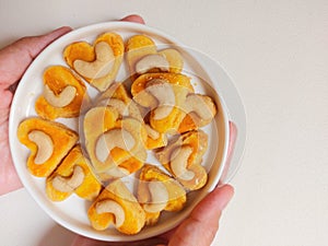 kue kering kacang mede or cashew cookies. made from butter, flour, egg and topped with cashew nut. served on white plate.