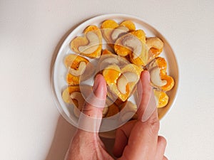 kue kering kacang mede or cashew cookies. made from butter, flour, egg and topped with cashew nut. served on white plate.