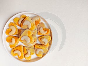 kue kering kacang mede or cashew cookies. made from butter, flour, egg and topped with cashew nut. served on white plate.