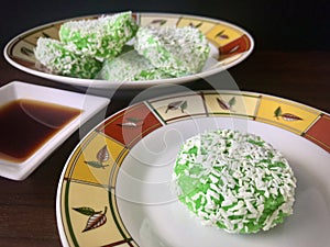 Kuih Lopes on a round plate, syrup on the side.