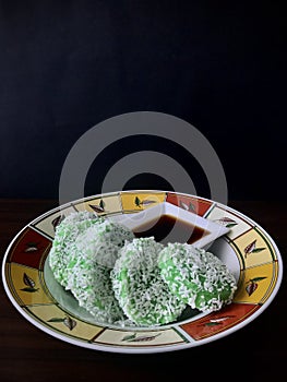 Kuih Lopes and syrup on a round plate. Vertical photo image.