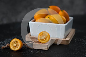 Kumquat fruit in a plate on a black table, citrus