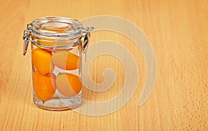 Kumquat inside a glass jar on wooden background