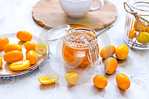 Kumquat on plate and jam in jar at gray background