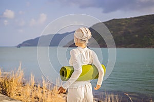 Kundalini yoga woman in white clothes and turban practices yoga kundalini on the background of the sea, mountains and
